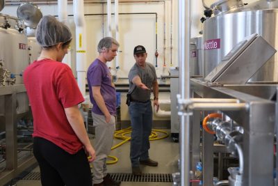 Two students are instructed on brewing in the VT campus brewery