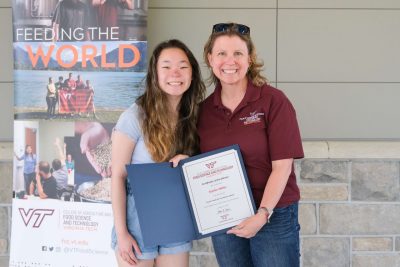 A student poses with an FST staff member and a certificate