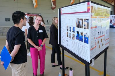 An undergraduate displays their research poster