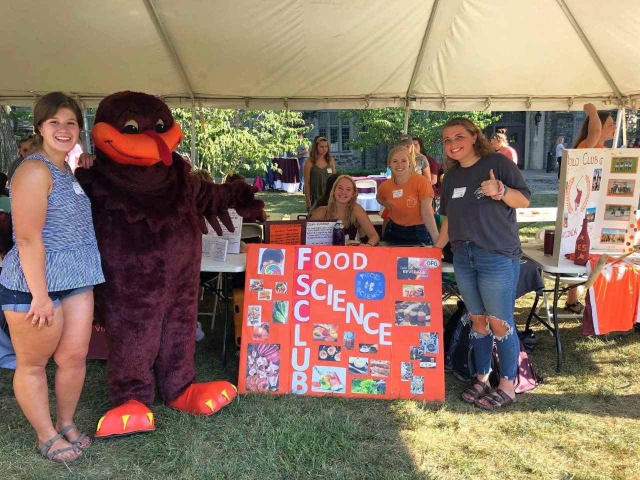 Food Science Club members pose with the Hokiebird in front of their table display.