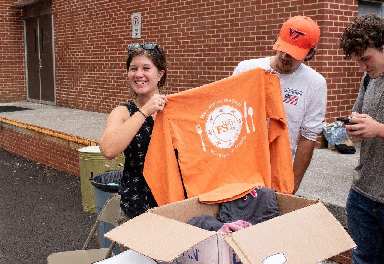 A student holds up Food Science Club t-shirt at a cookout event.
