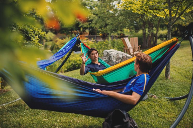 Two people sit in hammocks on campus