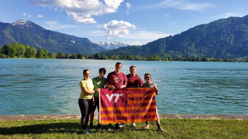 students holding VT flag in front of lake
