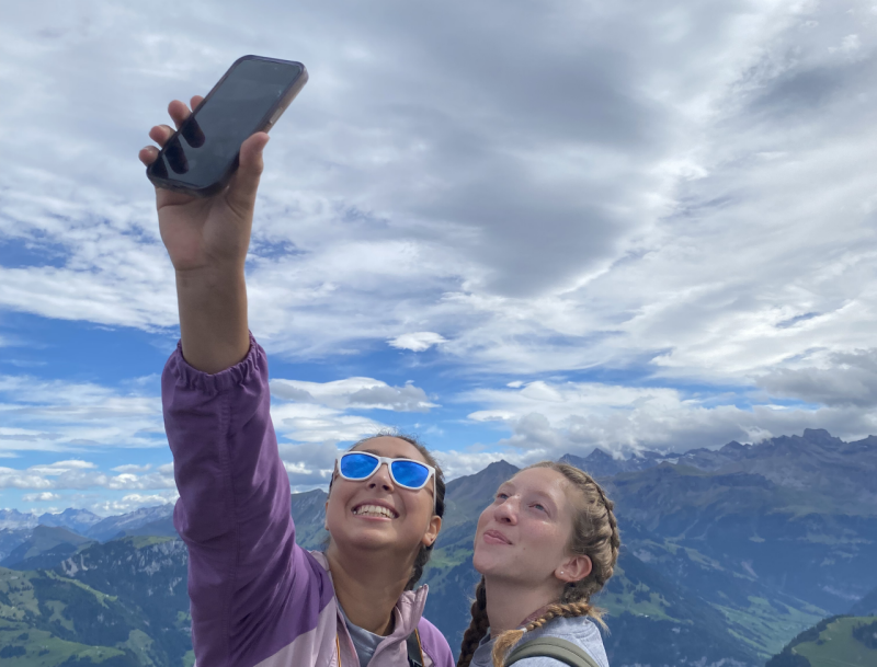 two female students taking a selfie at a lookout point while hiking