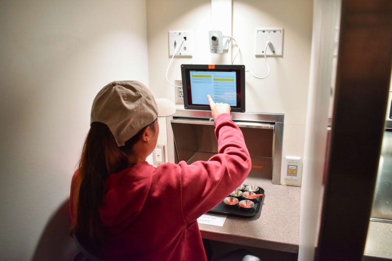 A researcher taps a screen inside a food sampling lab