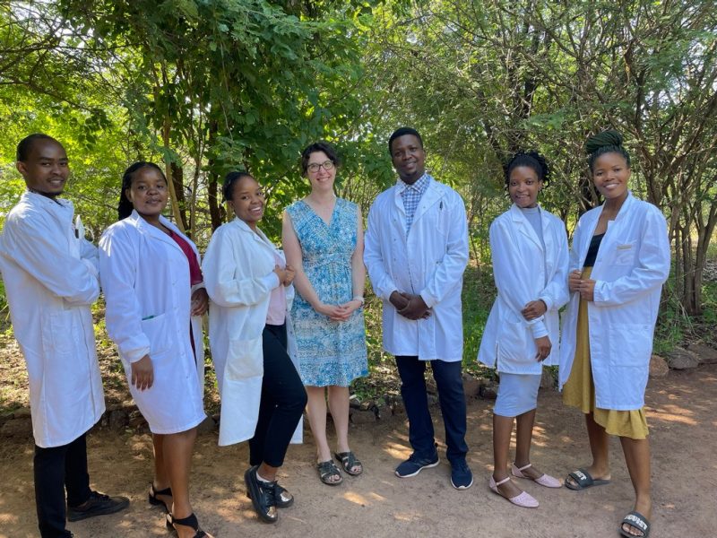 A group poses for a photo while wearing labcoats